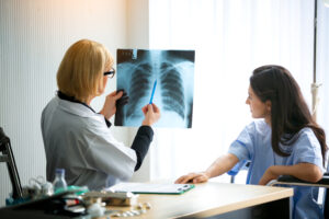 Doctor explaining lungs x-ray to women patient in clinic or Doctor in the office examining an x-ray and discussing with a patient